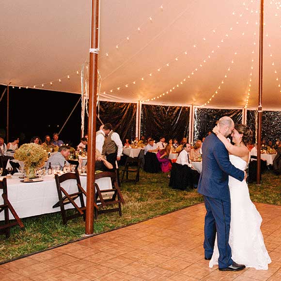 Couple dances under tent for outdoor night wedding
